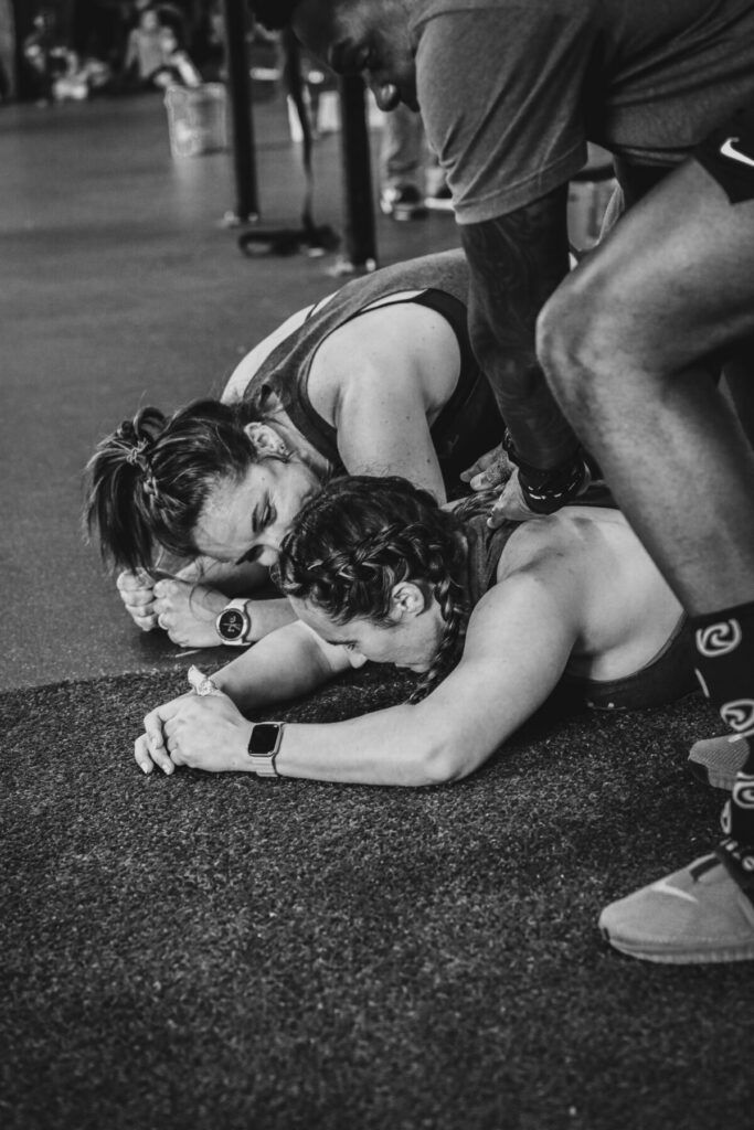 A black and white photo of two people doing push ups in a gym.