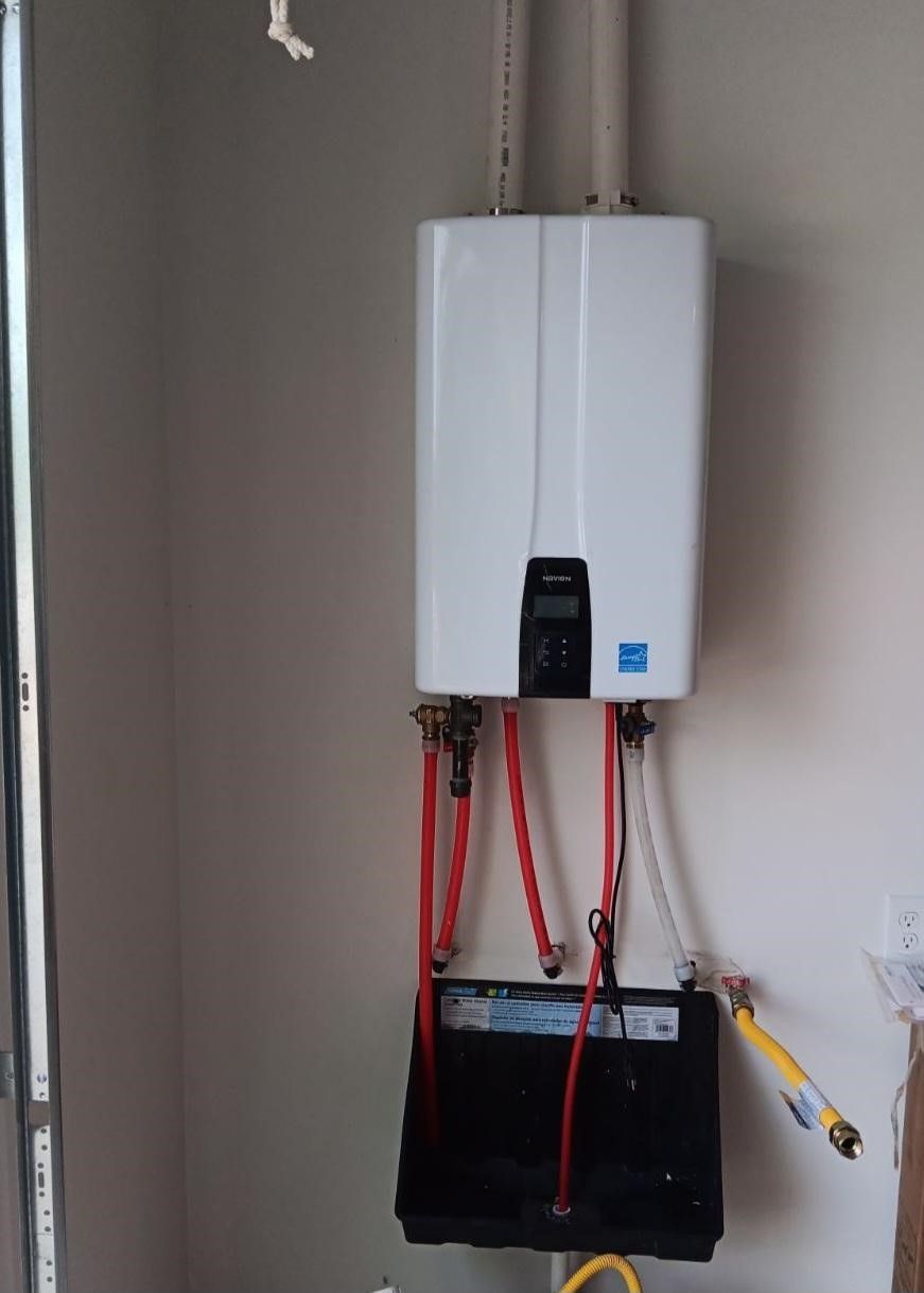 White tankless water heater on a wall with red and yellow pipes.
