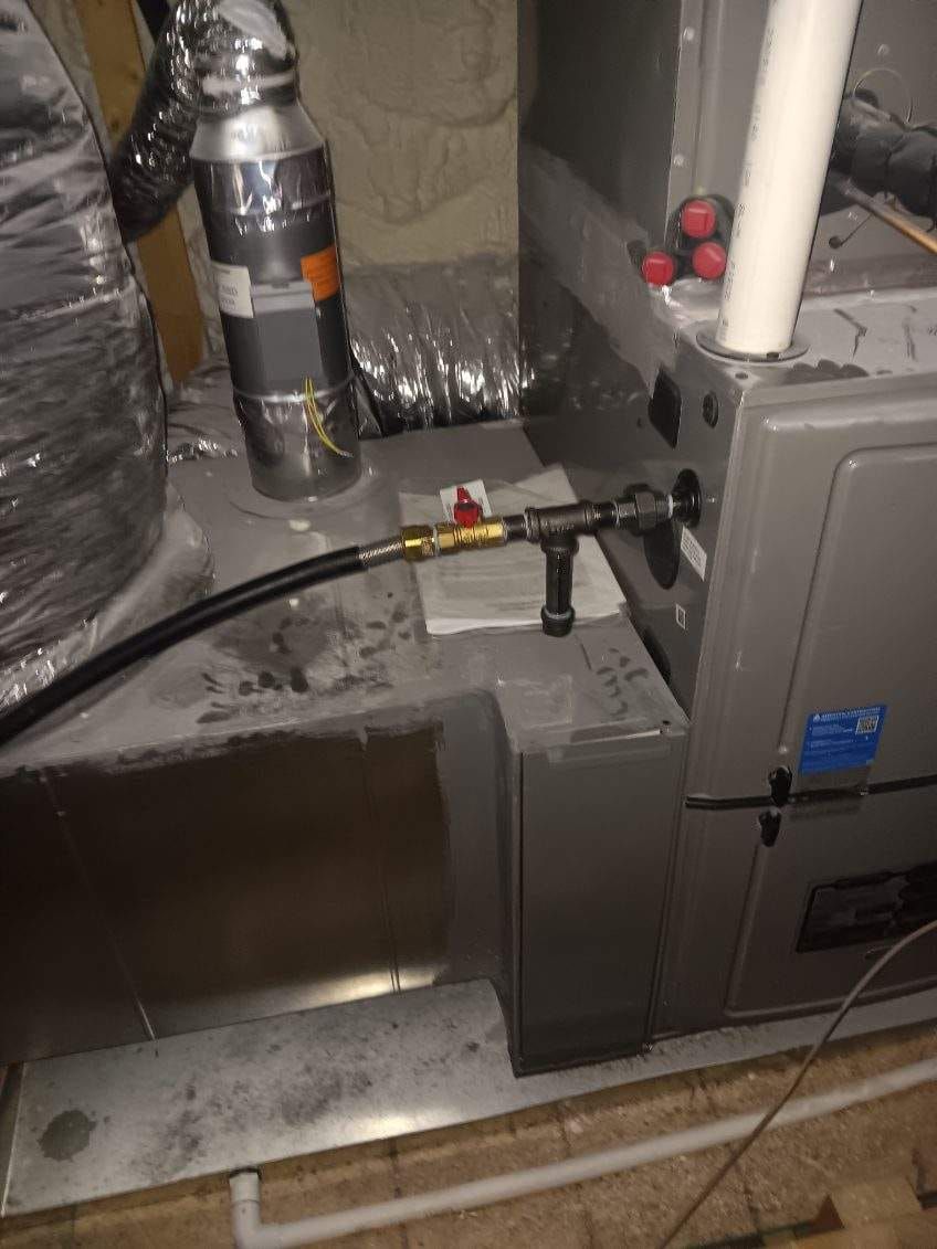 HVAC unit with gas line and ductwork in a basement setting.