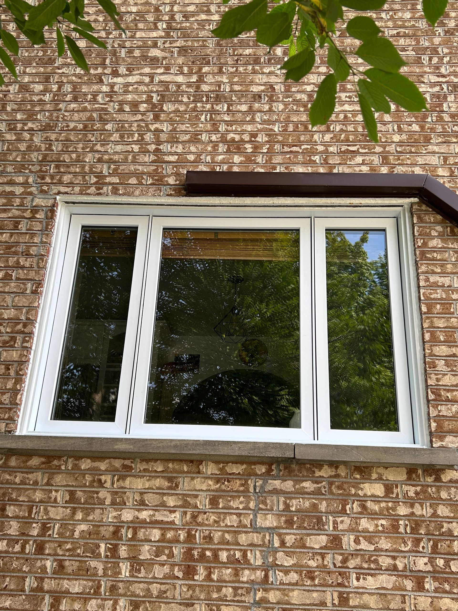 Une fenêtre blanche se trouve sur le côté d'un bâtiment en briques.