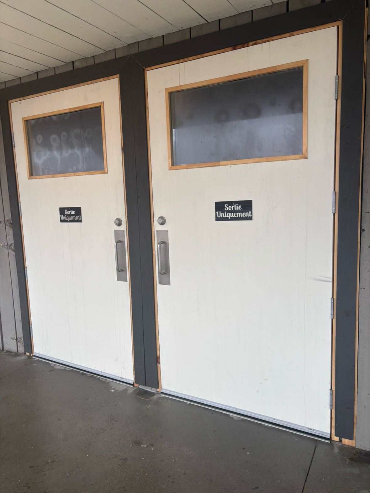 Deux portes blanches vitrées avec poignées en métal. Les panneaux indiquent « CUISINE » et « PETIT HAVRE ».