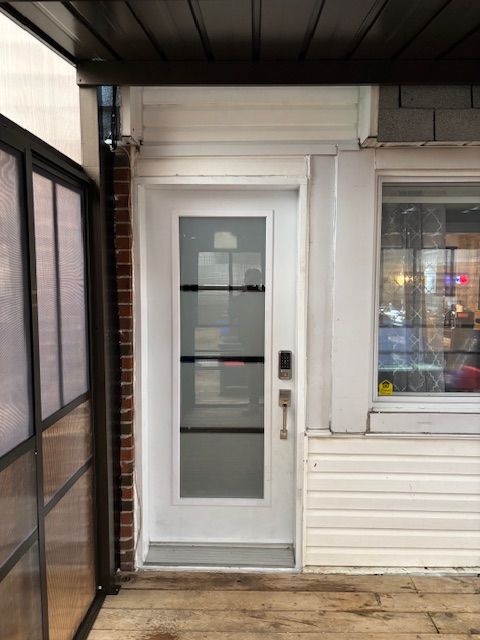 Une porte blanche avec une fenêtre en verre sur le côté d'une maison.