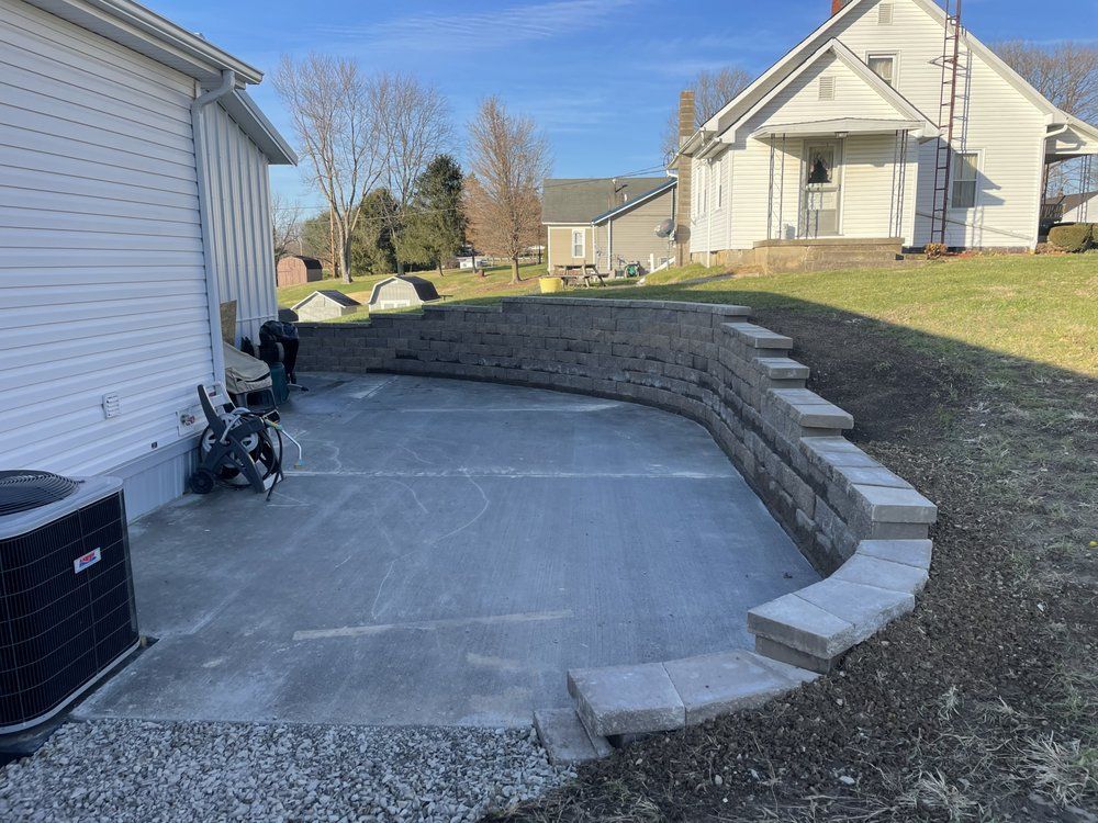 A concrete patio with a retaining wall in front of a house.