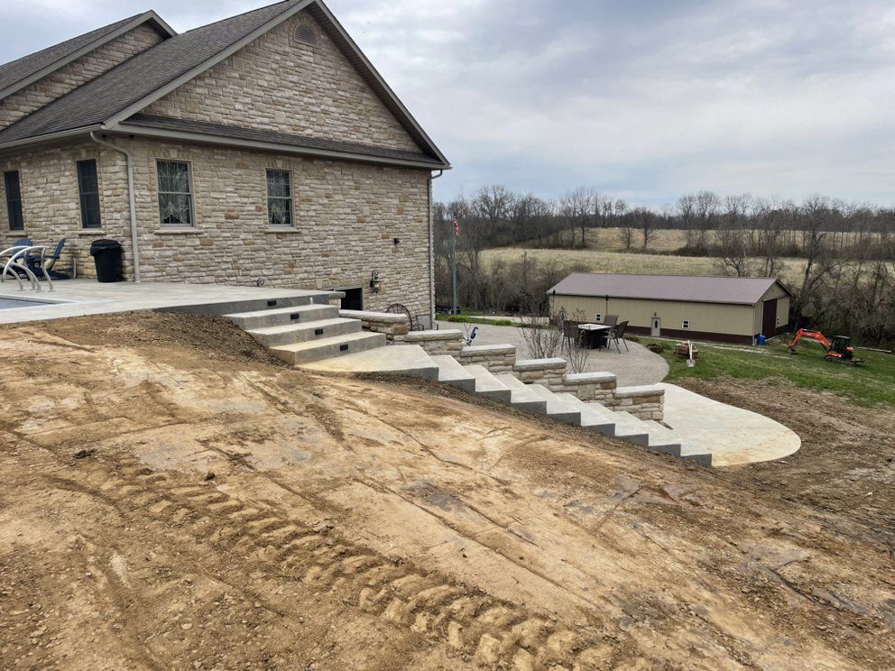 A concrete staircase is being built in front of a large stone house.