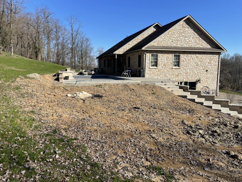 A large stone house is sitting on top of a hill surrounded by trees.