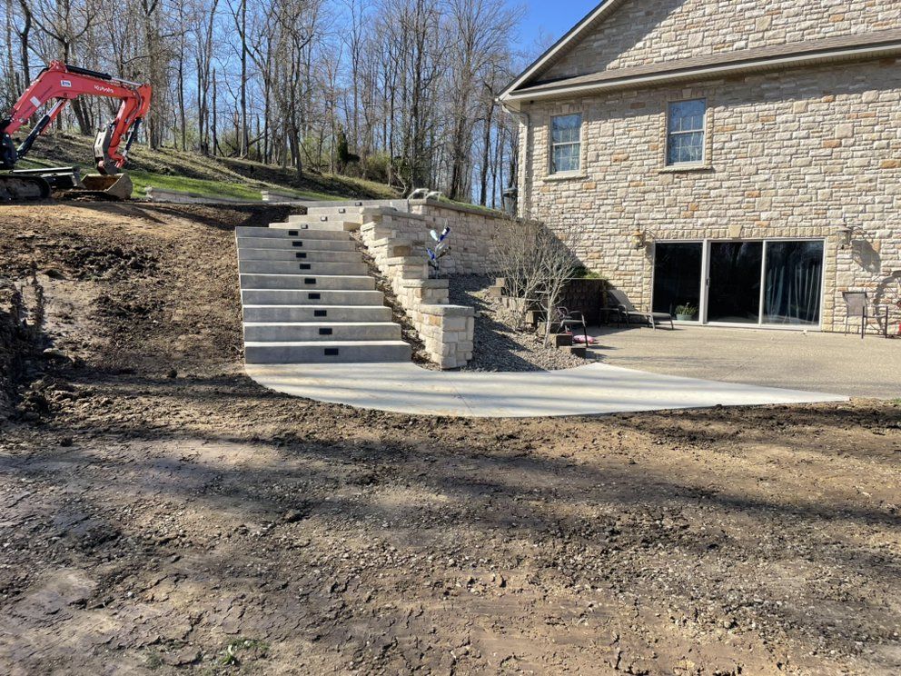 A concrete walkway is being built in front of a brick house.
