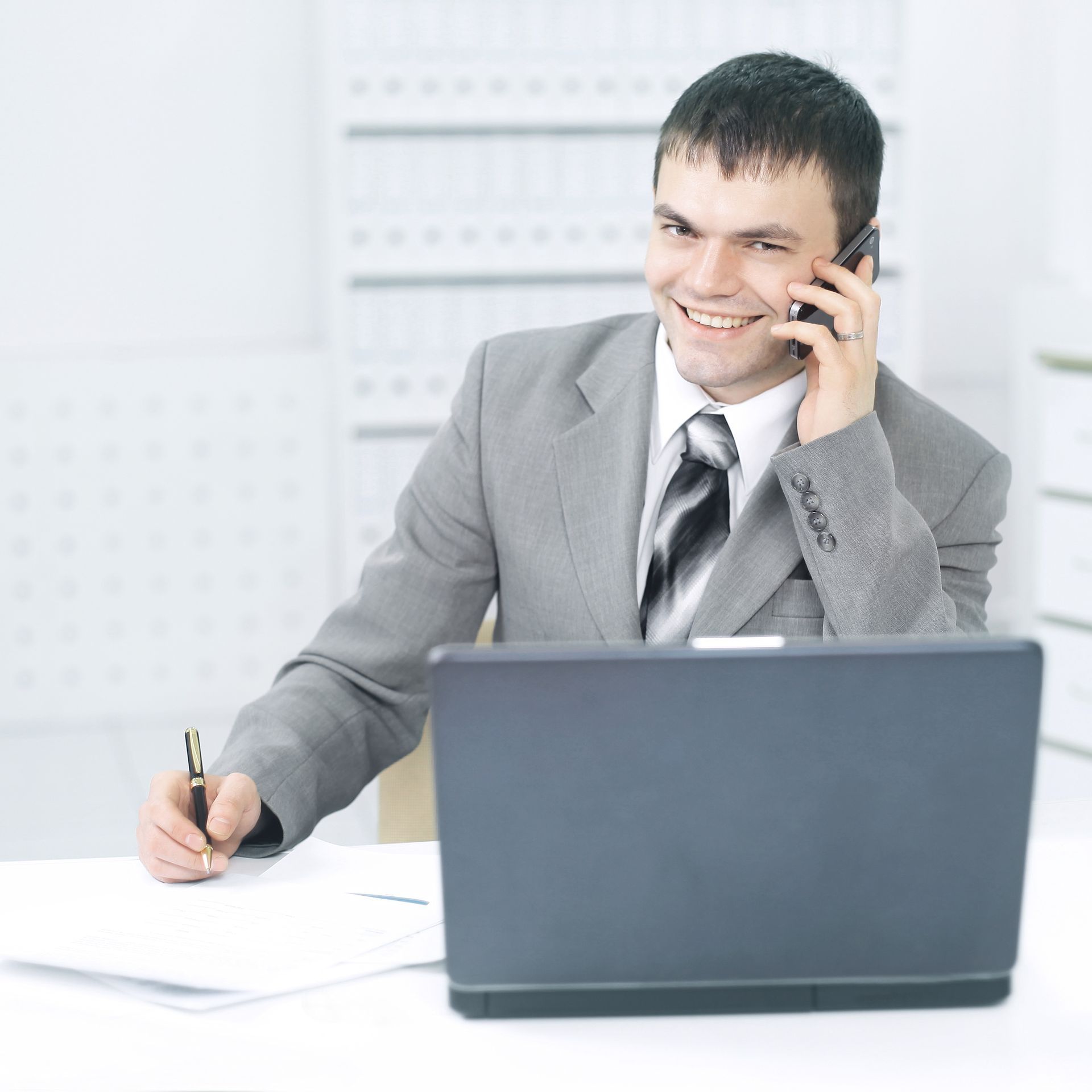 A male lawyer takes a call while writing on a notepad A male lawyer takes a call while writing on a notepad