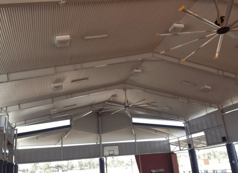 A large ceiling fan is hanging from the ceiling of a basketball court - Electrician in Emerald | All Saints Electrical