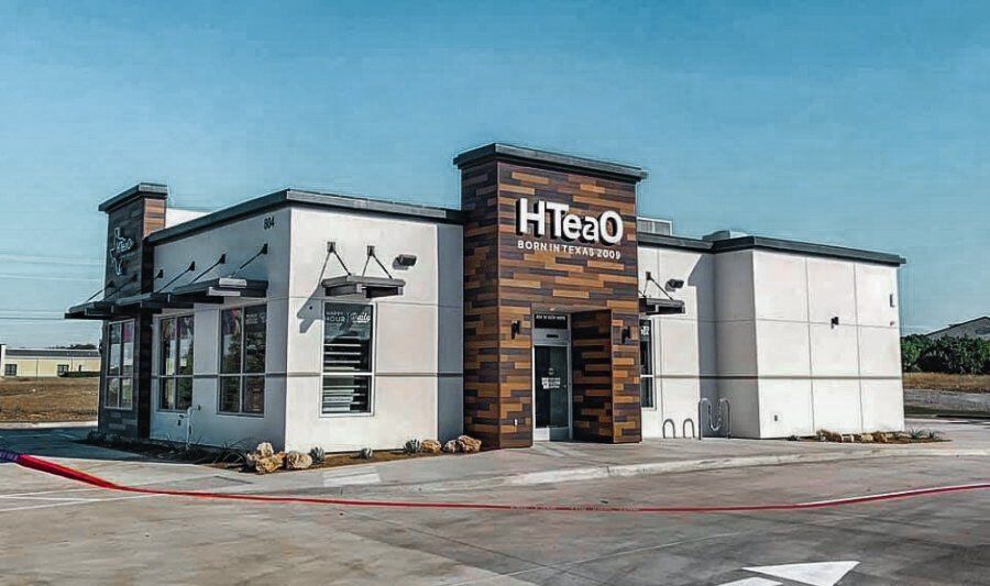 A white building with a wooden facade is sitting on top of a concrete lot.