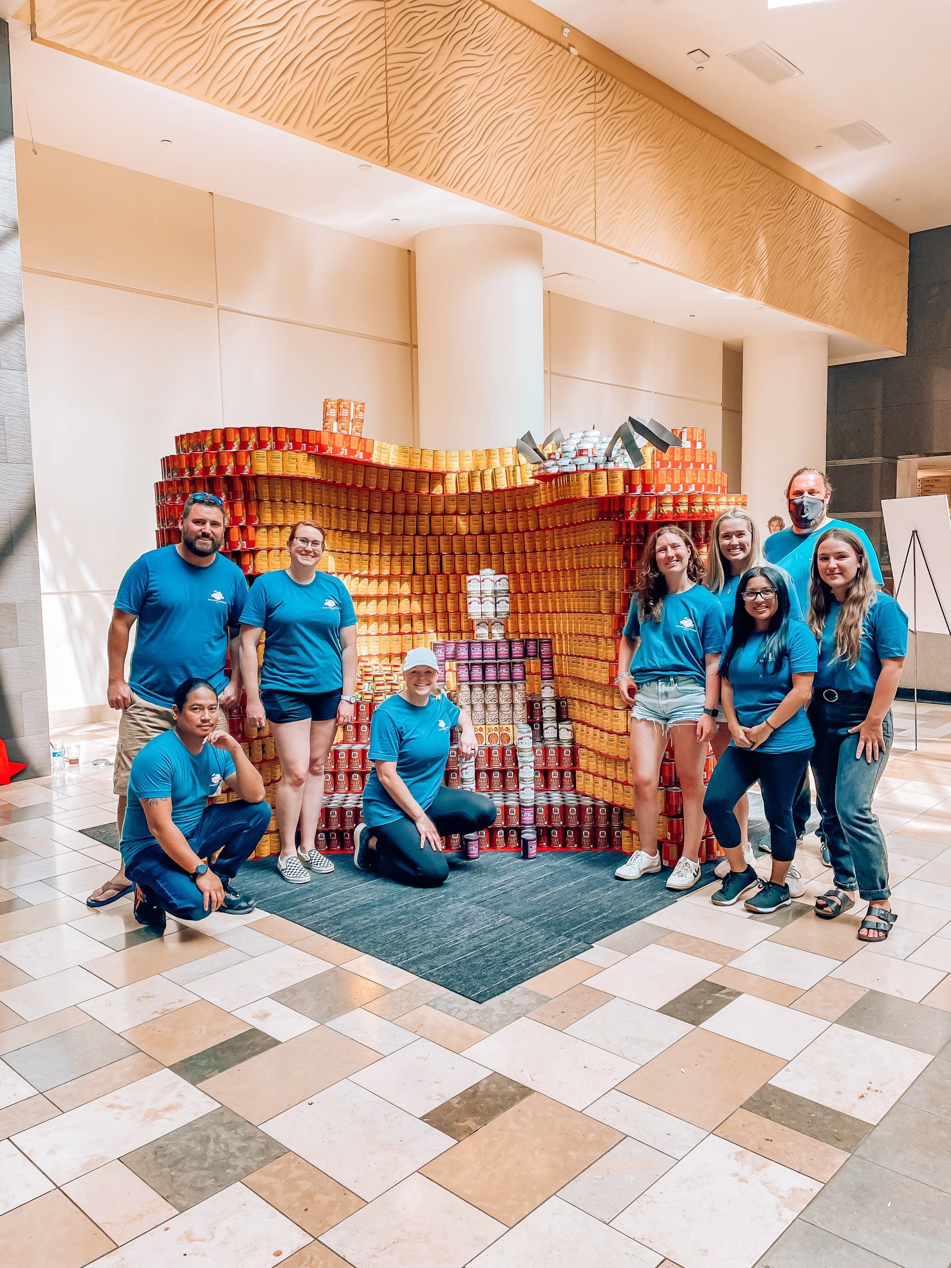 A group of people are posing for a picture in front of a sculpture made out of cans.