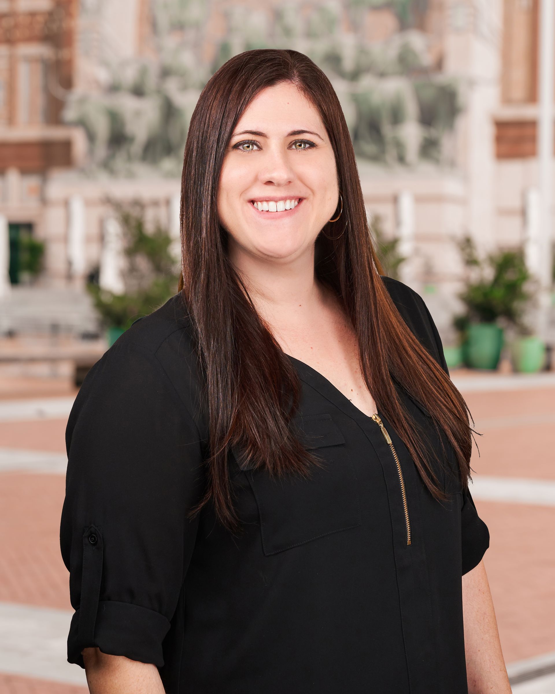 A woman in a black shirt is smiling in front of a church.