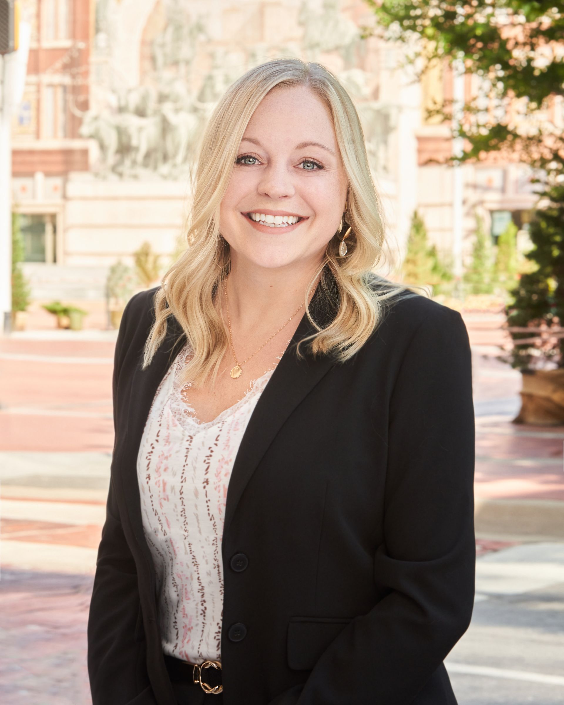 A woman in a black jacket and white shirt is smiling for the camera.