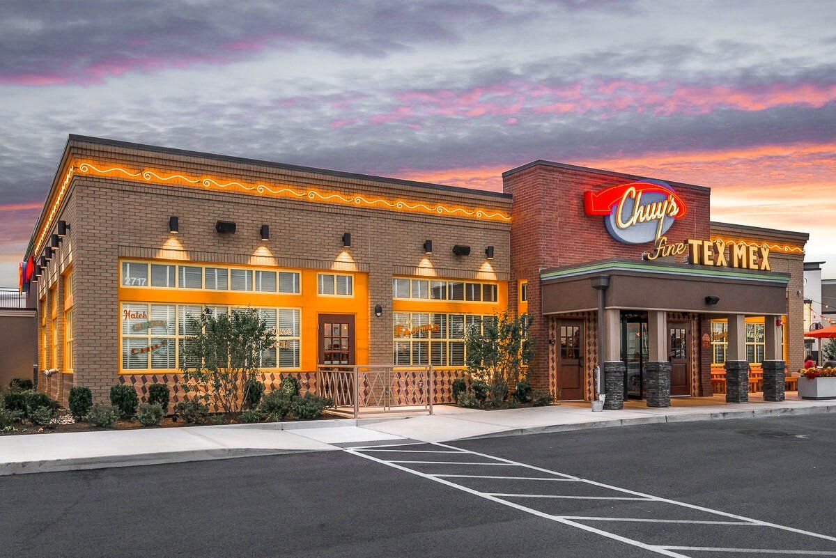 A large building with a lot of windows and a parking lot in front of it.