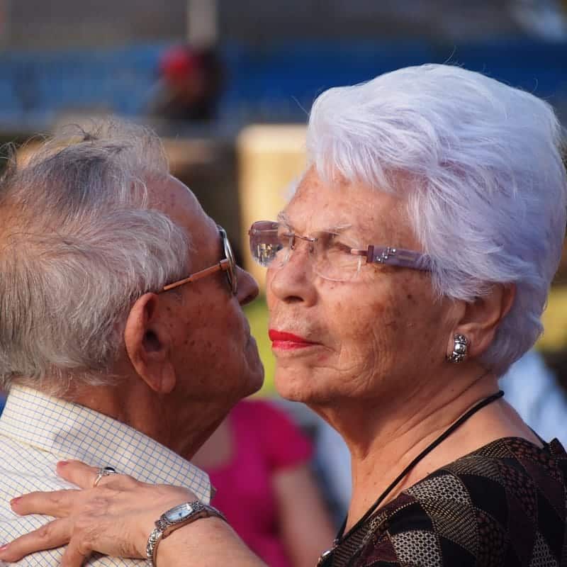 A man and a woman are dancing and the woman is wearing glasses
