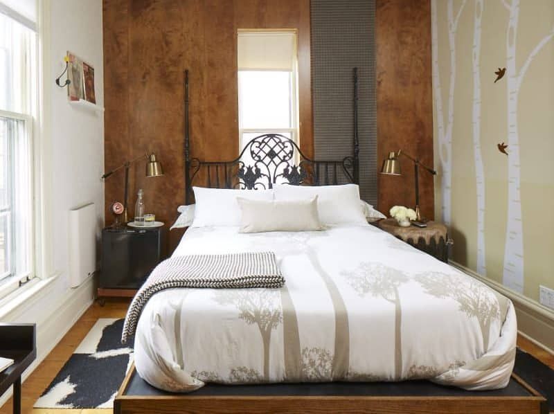 A bedroom with a bed and a window with trees painted on the wall