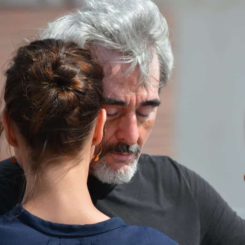 A man with a beard is looking at a woman 's back.