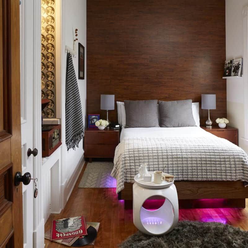 A bedroom with a bed and a nightstand with a book on the floor that says bake off