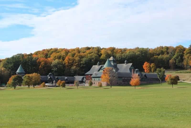 A large building in the middle of a field with trees in the background.