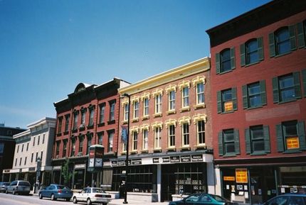 A row of brick buildings with green shutters on the windows