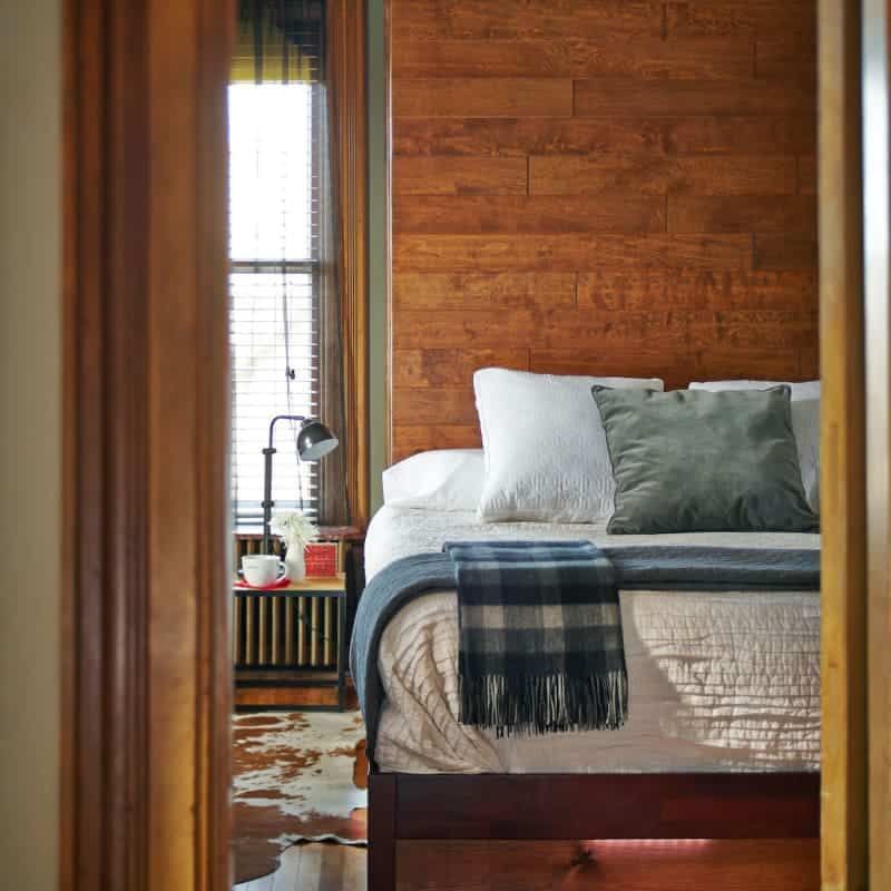 A bedroom with a bed and a wooden headboard