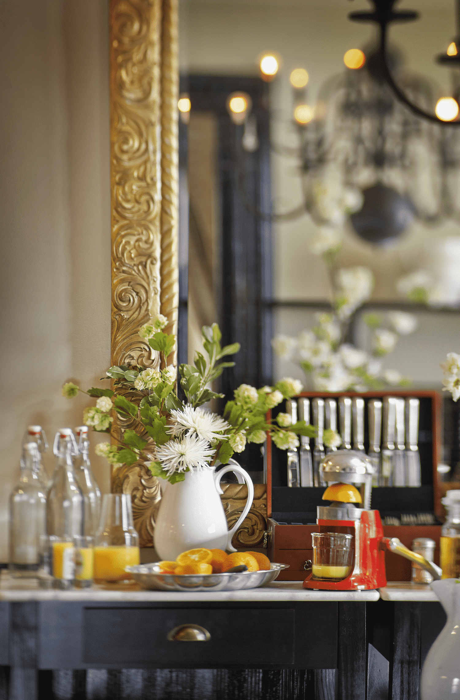A table with a vase of flowers and bottles of orange juice on it