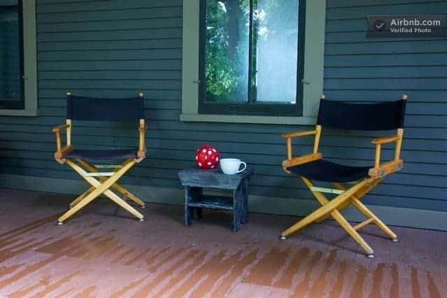 Two director 's chairs sit on a porch next to a small table