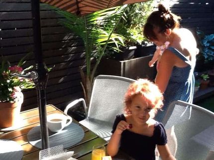 A little girl sitting at a table with a cup of coffee