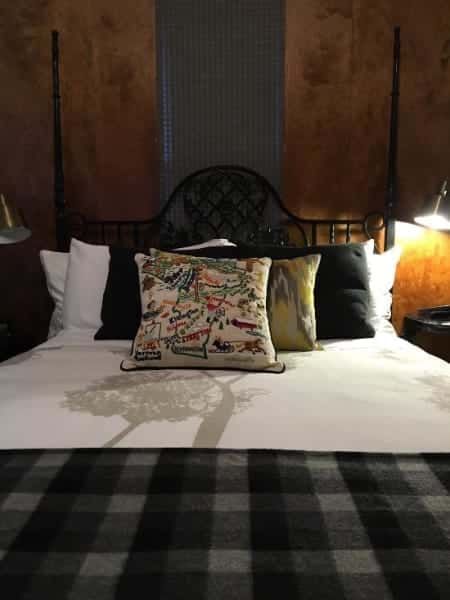 A bed with a plaid blanket and pillows on it