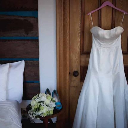 A white wedding dress is hanging on a pink hanger