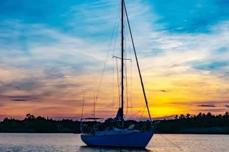 A sailboat is docked in the water at sunset.