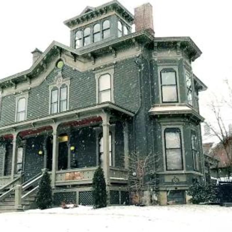 A large house with a porch in the snow.
