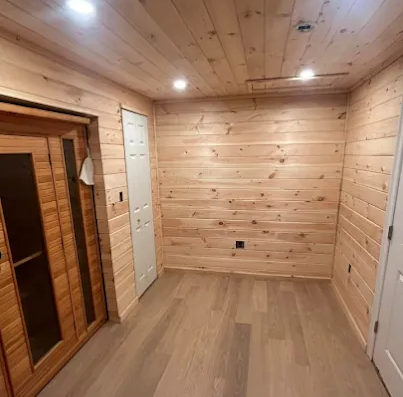 Spacious finished basement with a pool table, black leather seating, and large windows.
