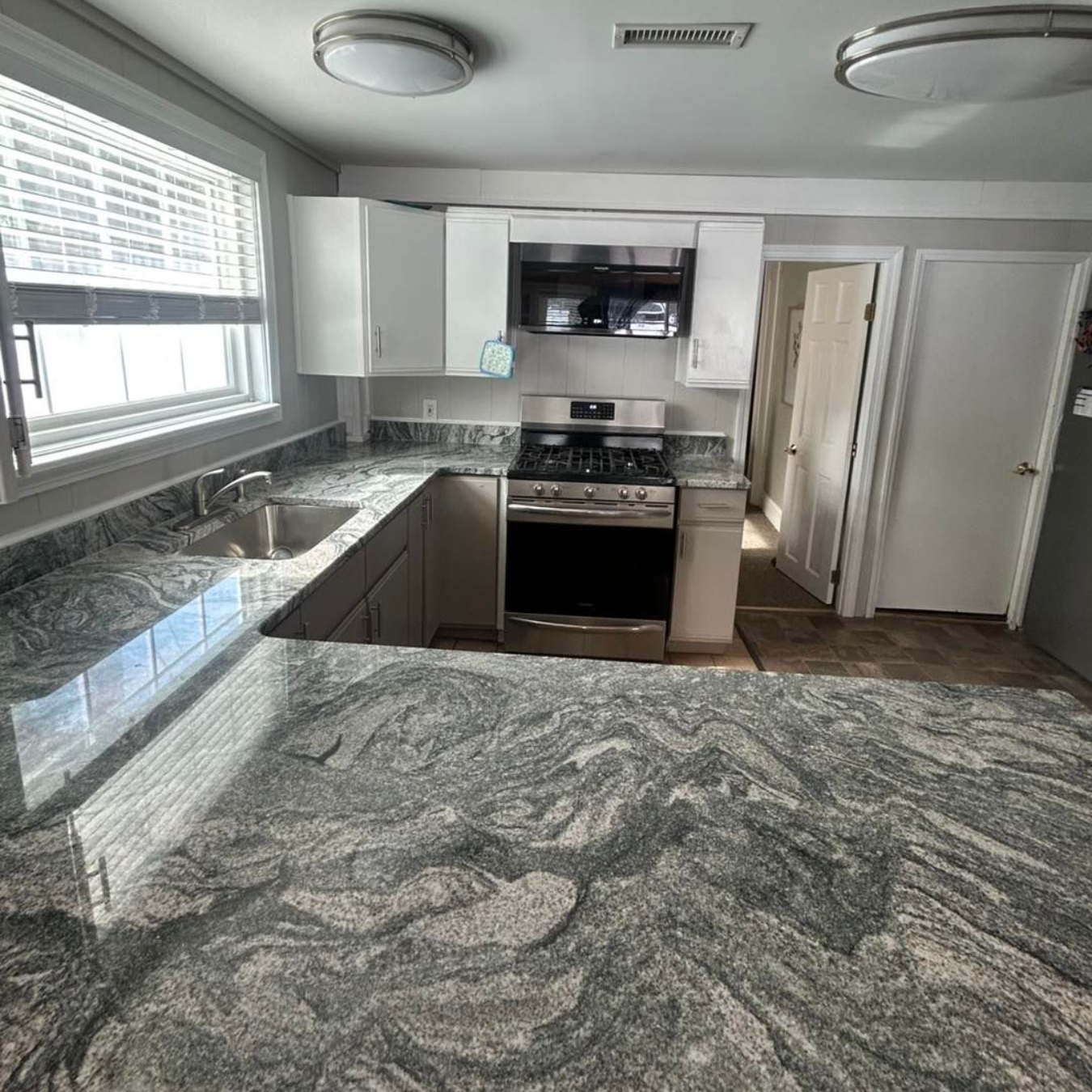Modern kitchen with island seating, light wood cabinets, and glass-fronted storage; opens to outdoor patio.