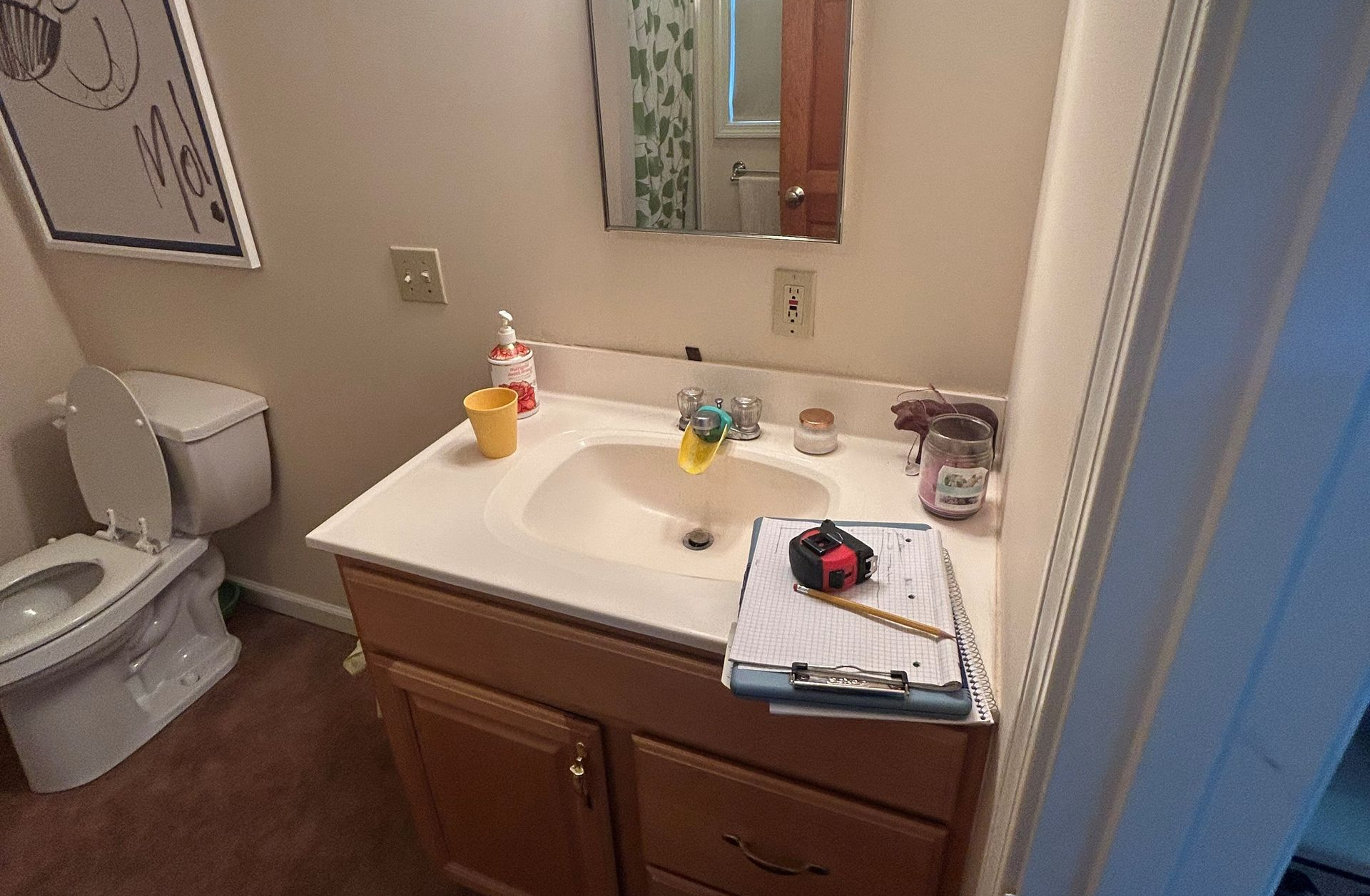 Modern bathroom with wooden vanity, large mirror, marble shower, and flooring.