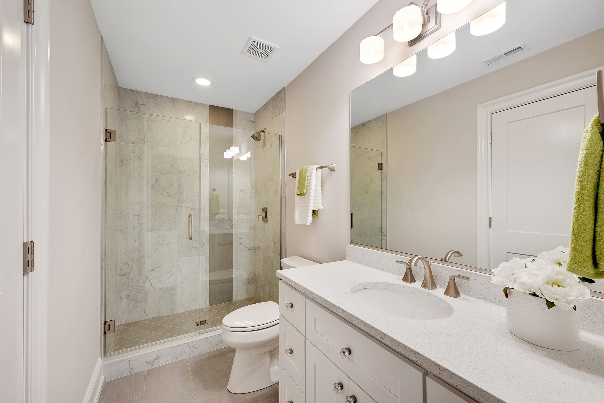Modern bathroom with a glass shower, white vanity, and toilet.