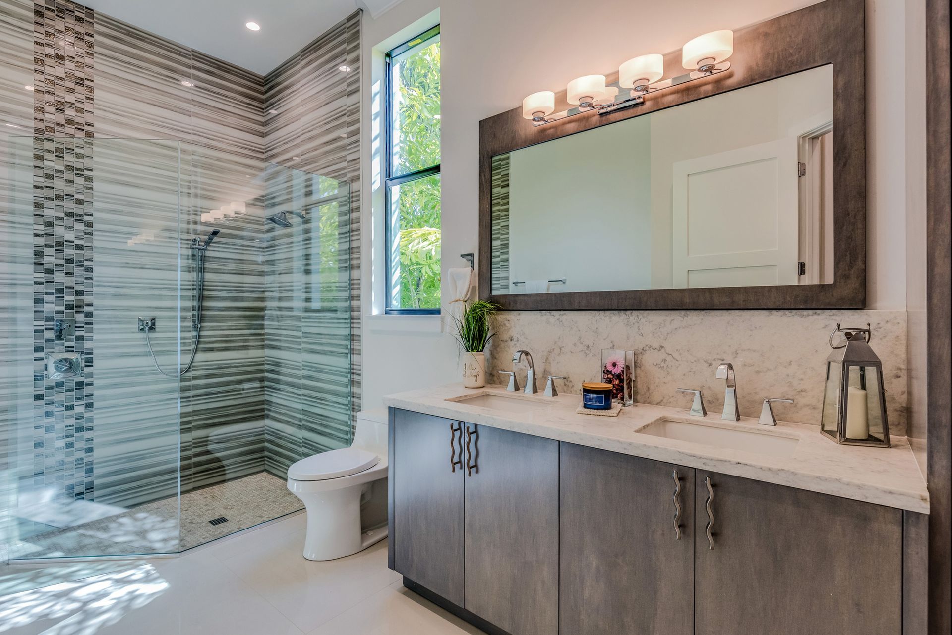 Modern bathroom with gray double vanity, shower, and a window.