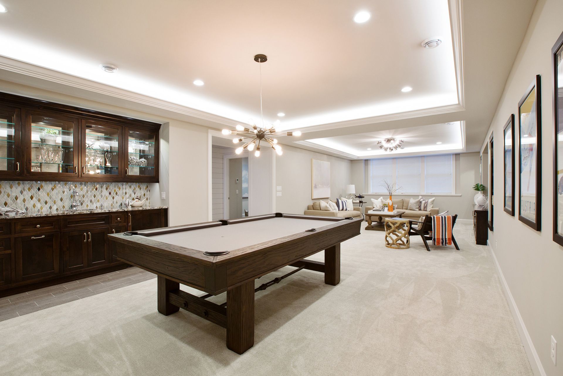 Pool table in a finished basement with a bar, seating area, and multiple light fixtures.