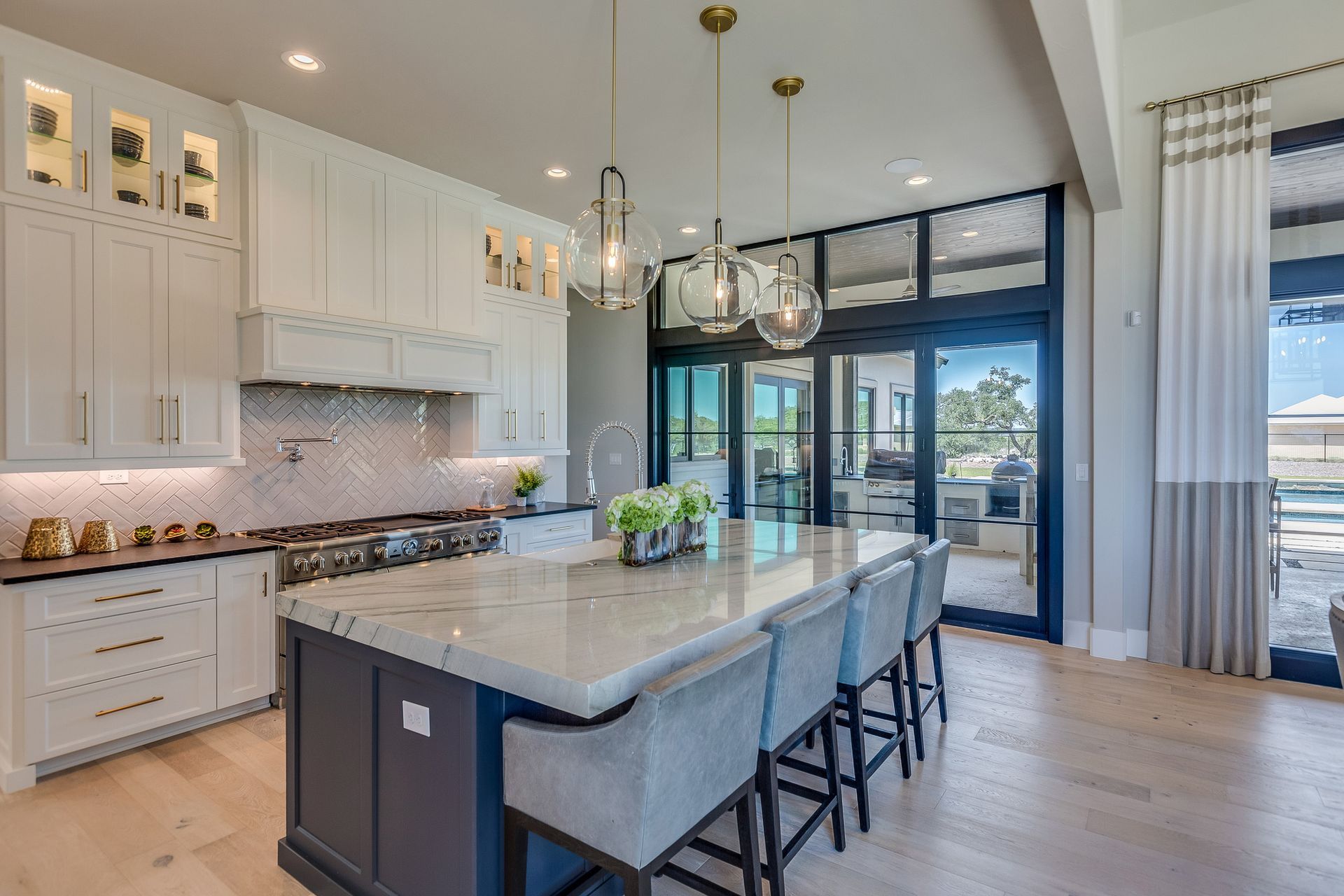 Elegant white kitchen with island, blue accents, and large windows.