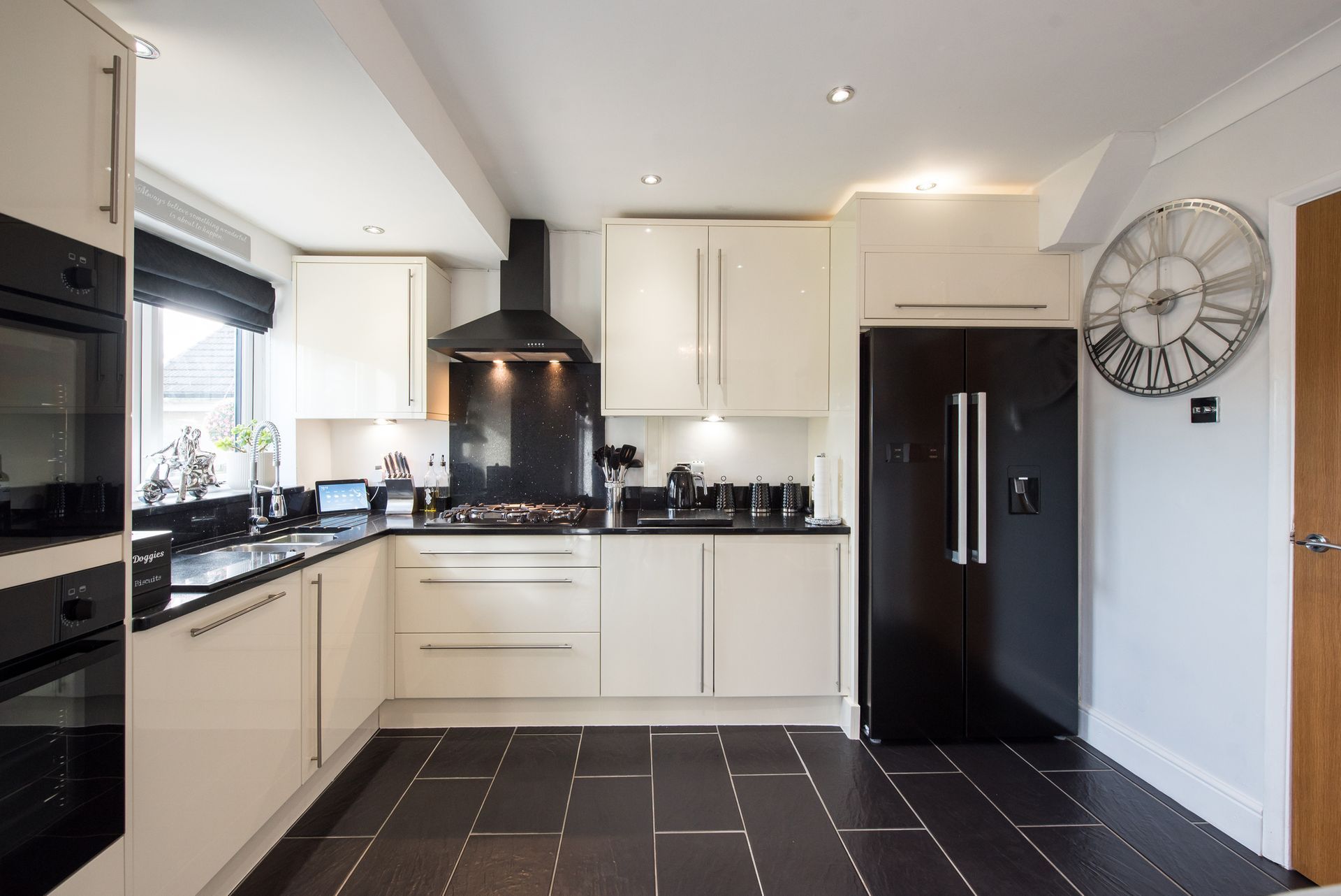 Modern kitchen with island, wood floors, white and gray cabinets, two pendant lights.