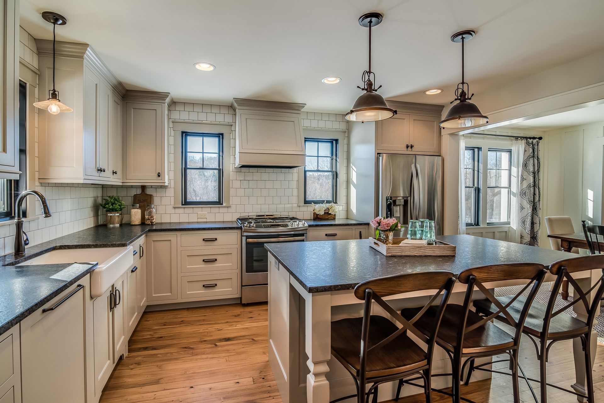 Modern kitchen with white cabinets, black countertops, and a kitchen island with bar stools.