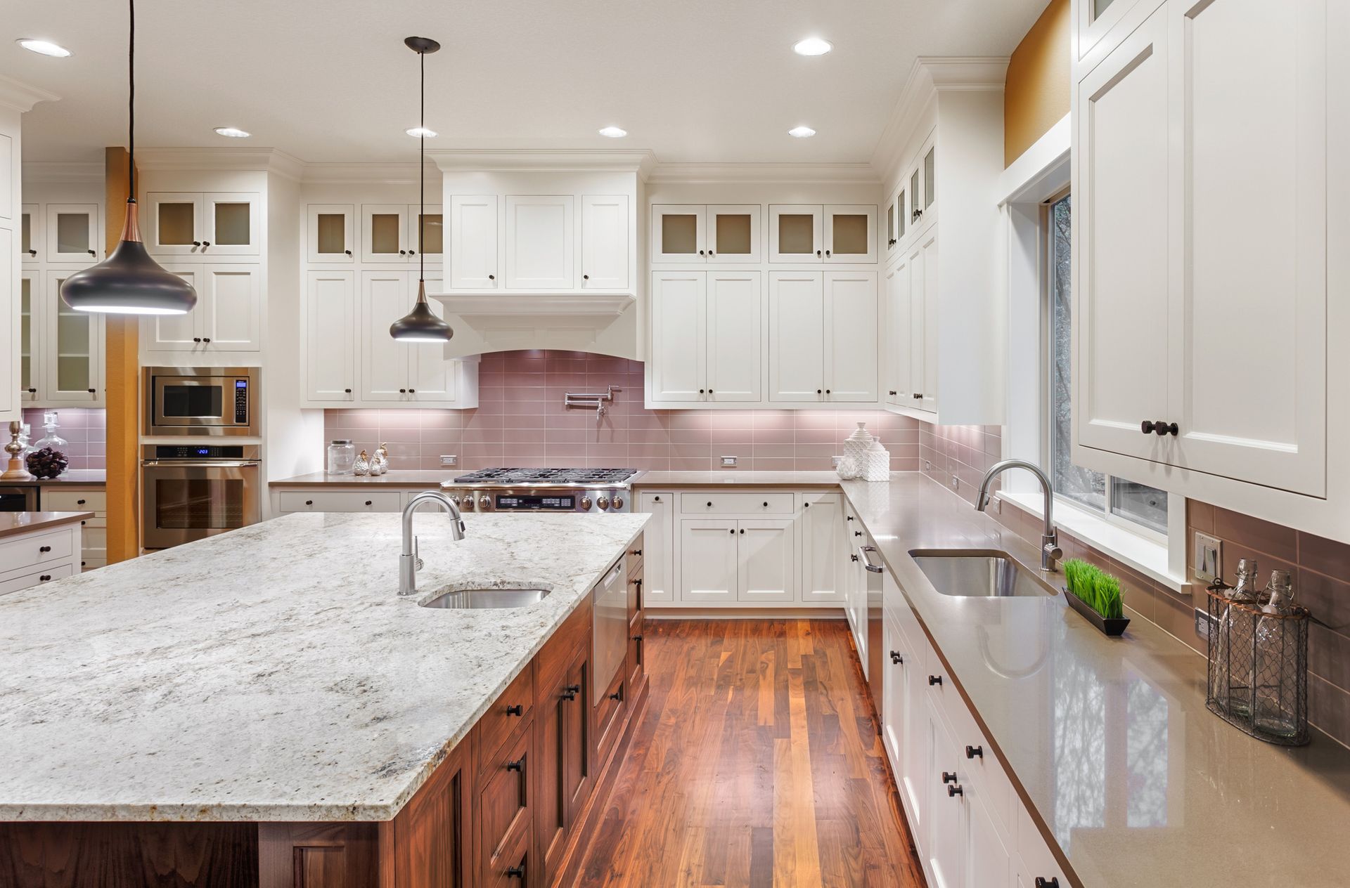 Kitchen with a large island, white cabinets, granite countertops, and wood floors.
