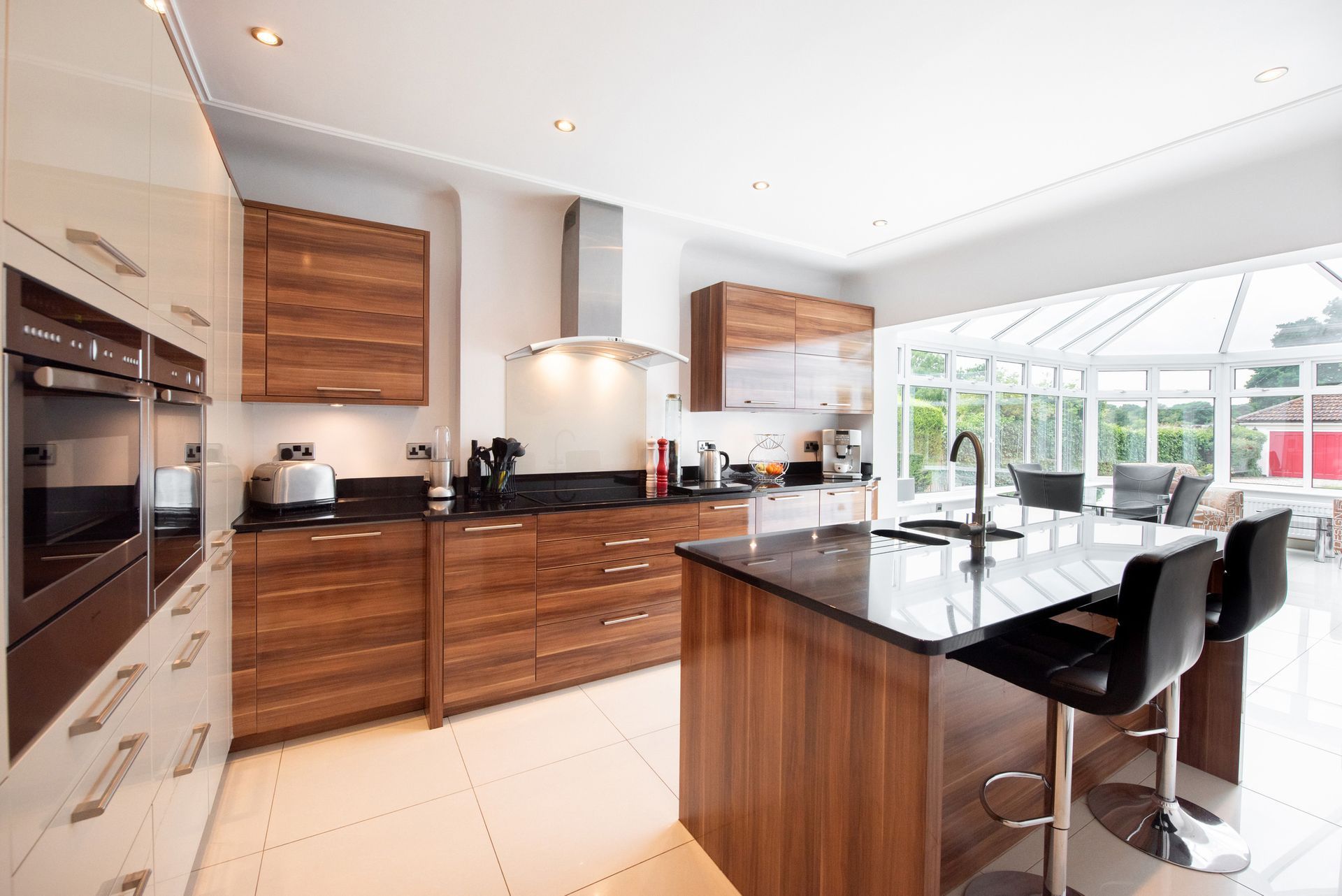 Modern kitchen with dark wood cabinets, stainless steel appliances, and a black island with bar stools.