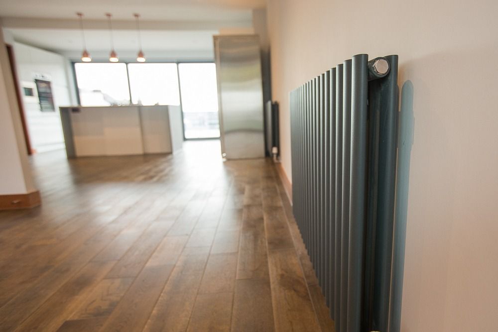 Modern hallway with vertical radiator and open kitchen in background.