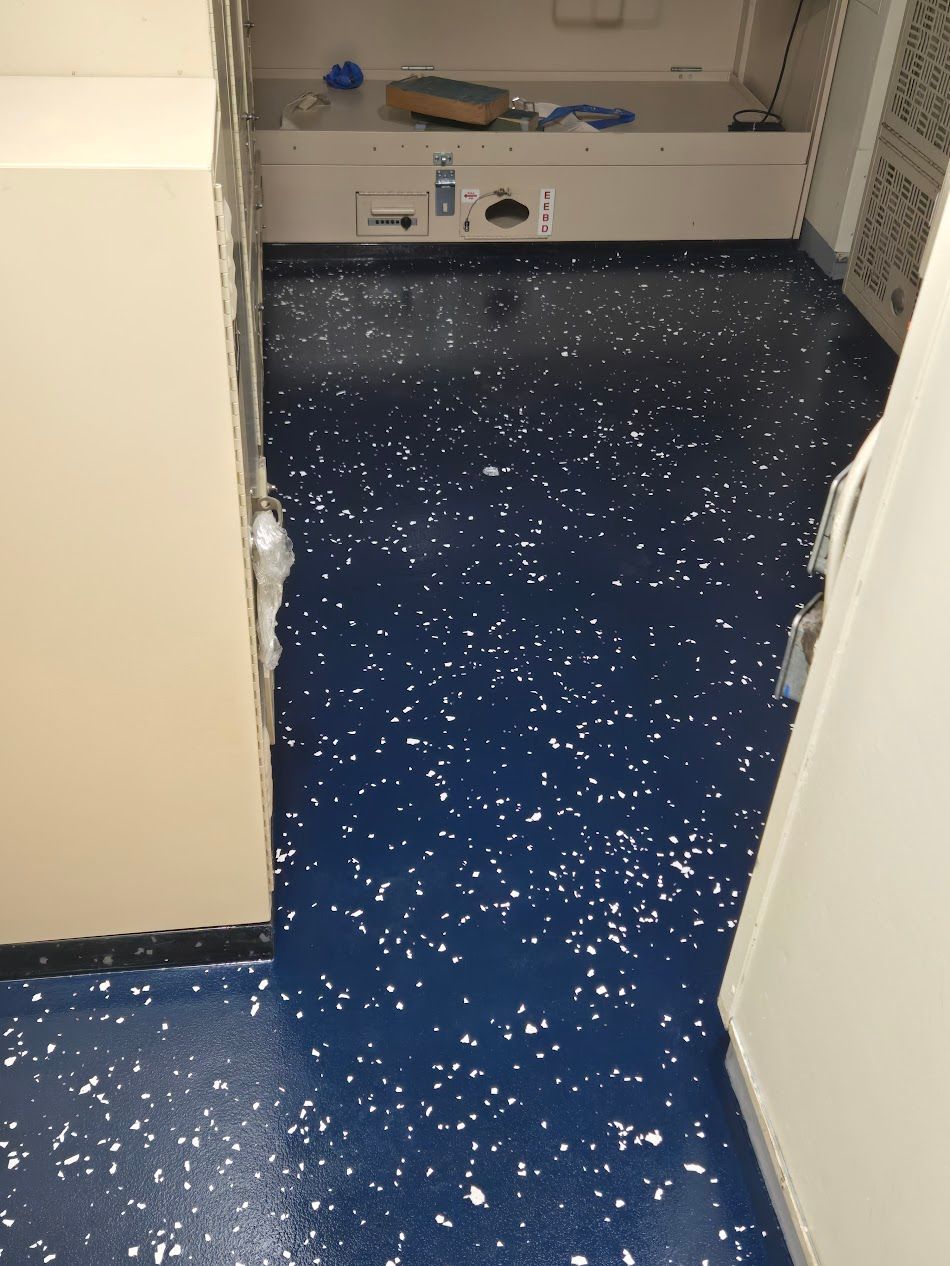 Blue speckled floor in a lab, surrounded by white cabinets and walls.