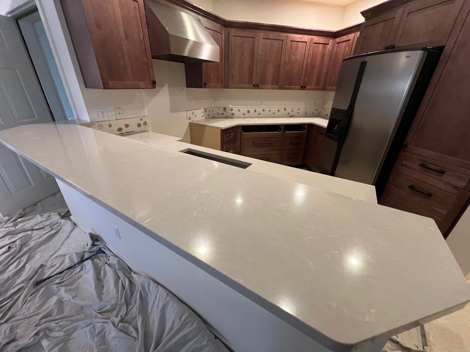 Kitchen with light gray countertop, dark wood cabinets, stainless steel appliances.