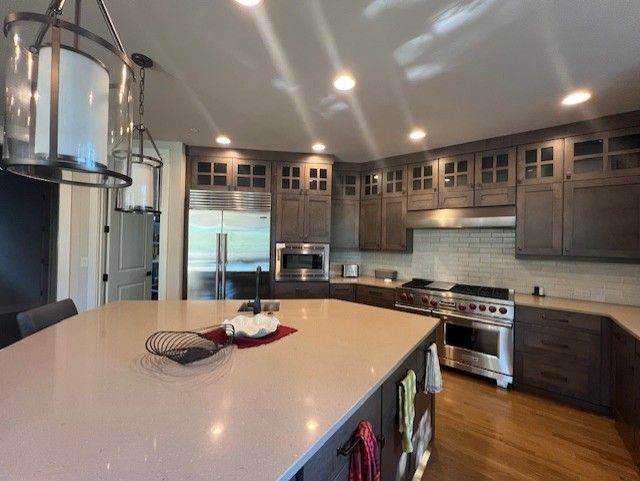 Spacious, modern kitchen with large island, stainless steel appliances, and dark cabinets.