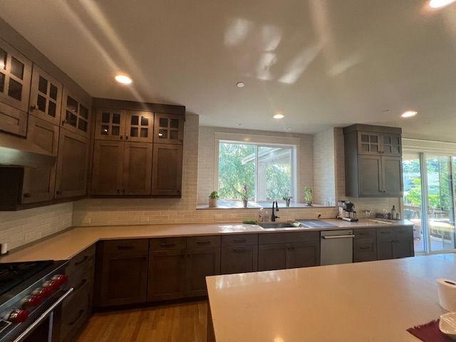 Dark brown kitchen cabinets with light countertops and a window with natural light.