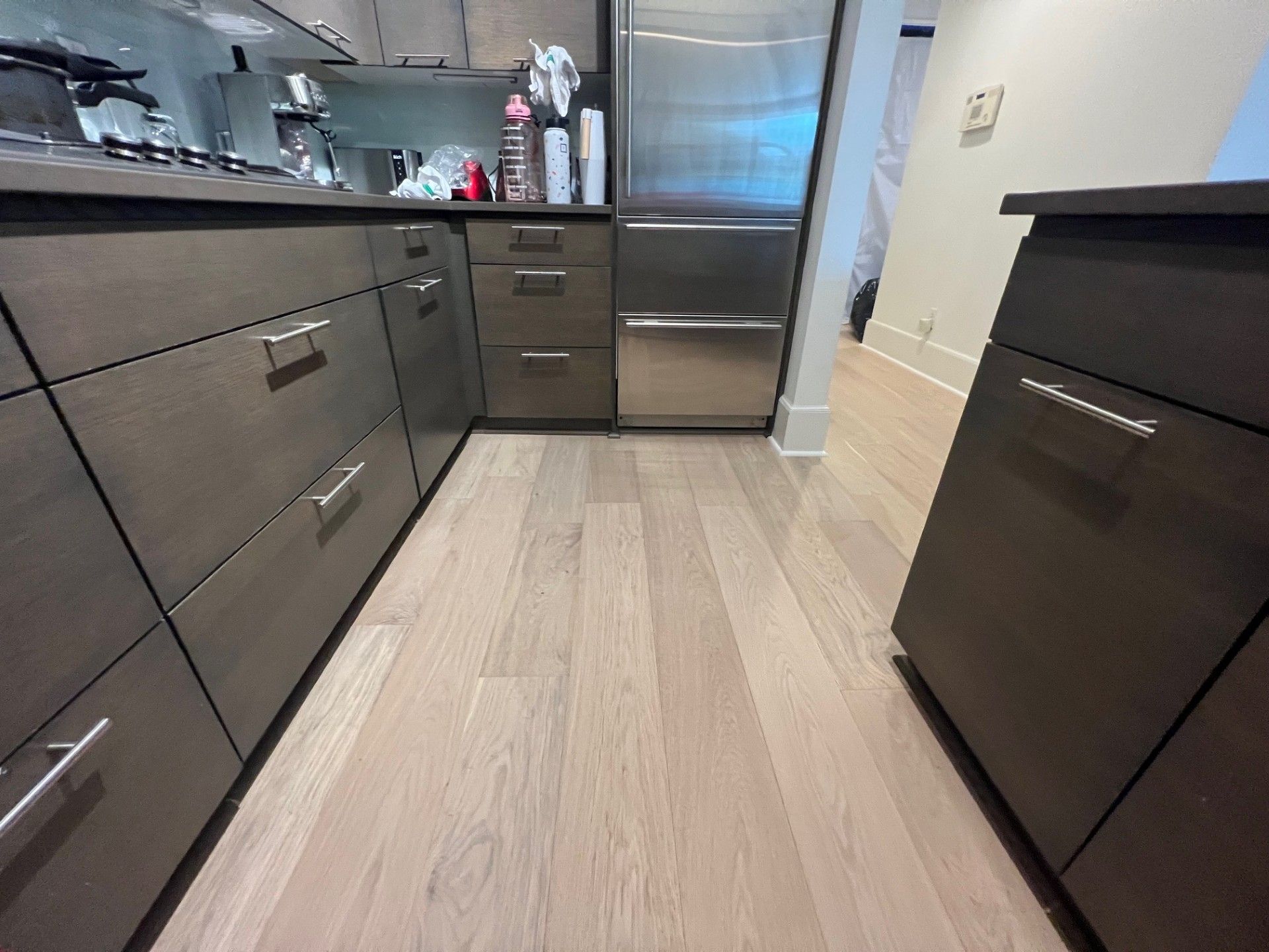 Kitchen with light wooden floors, dark brown cabinets, and stainless steel refrigerator.