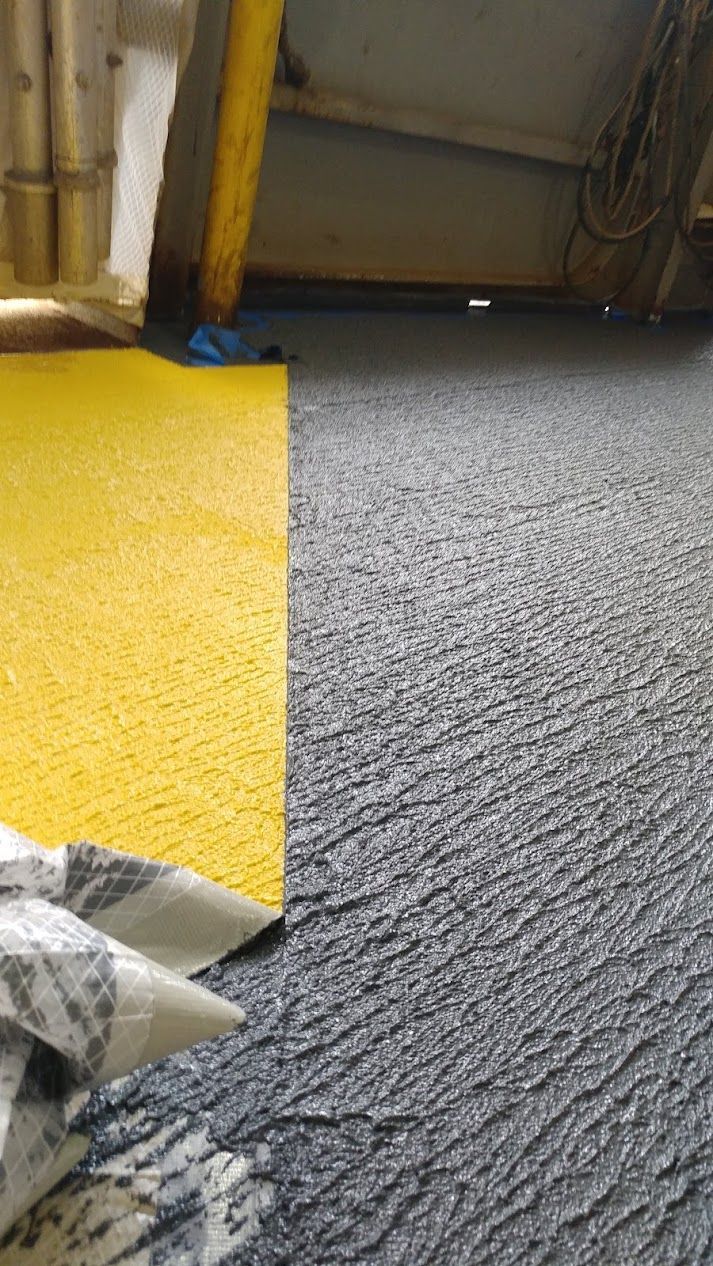 Yellow floor mat next to a textured, gray surface; an overhead view.