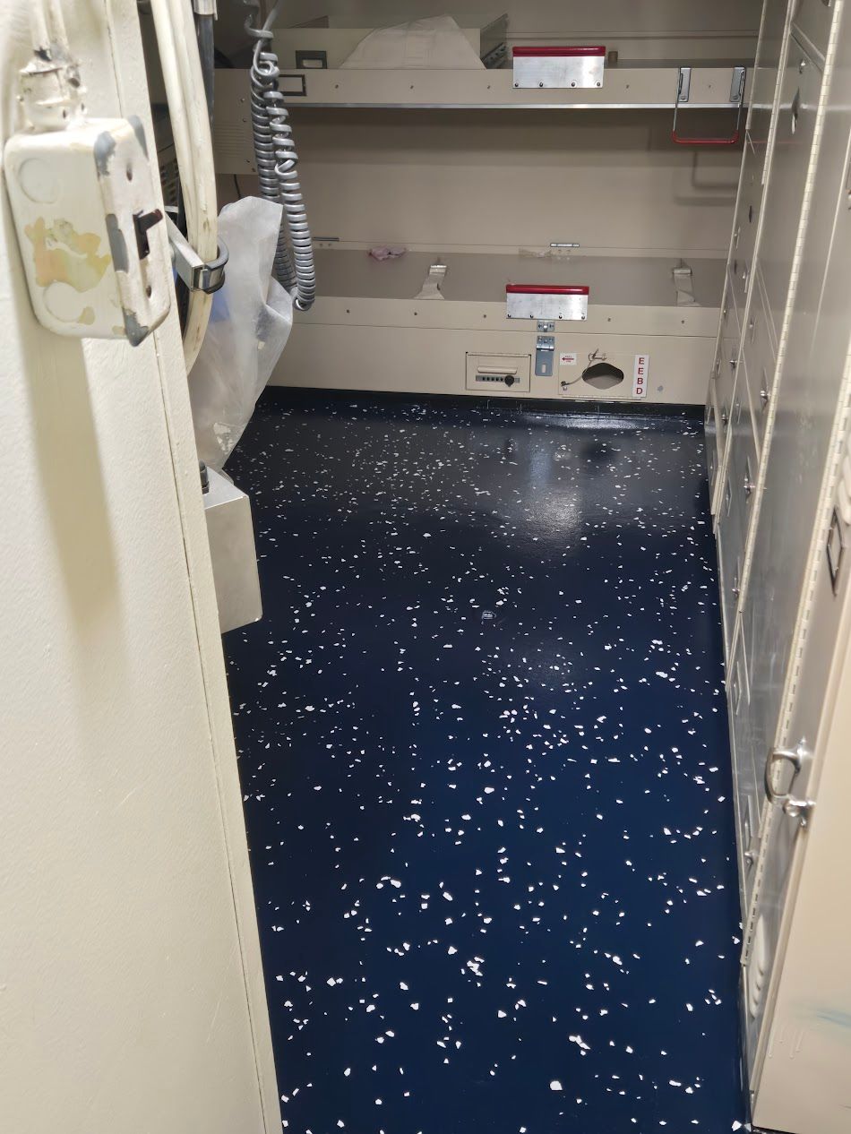 An open room with blue speckled floor and white walls. A door is ajar on the left.